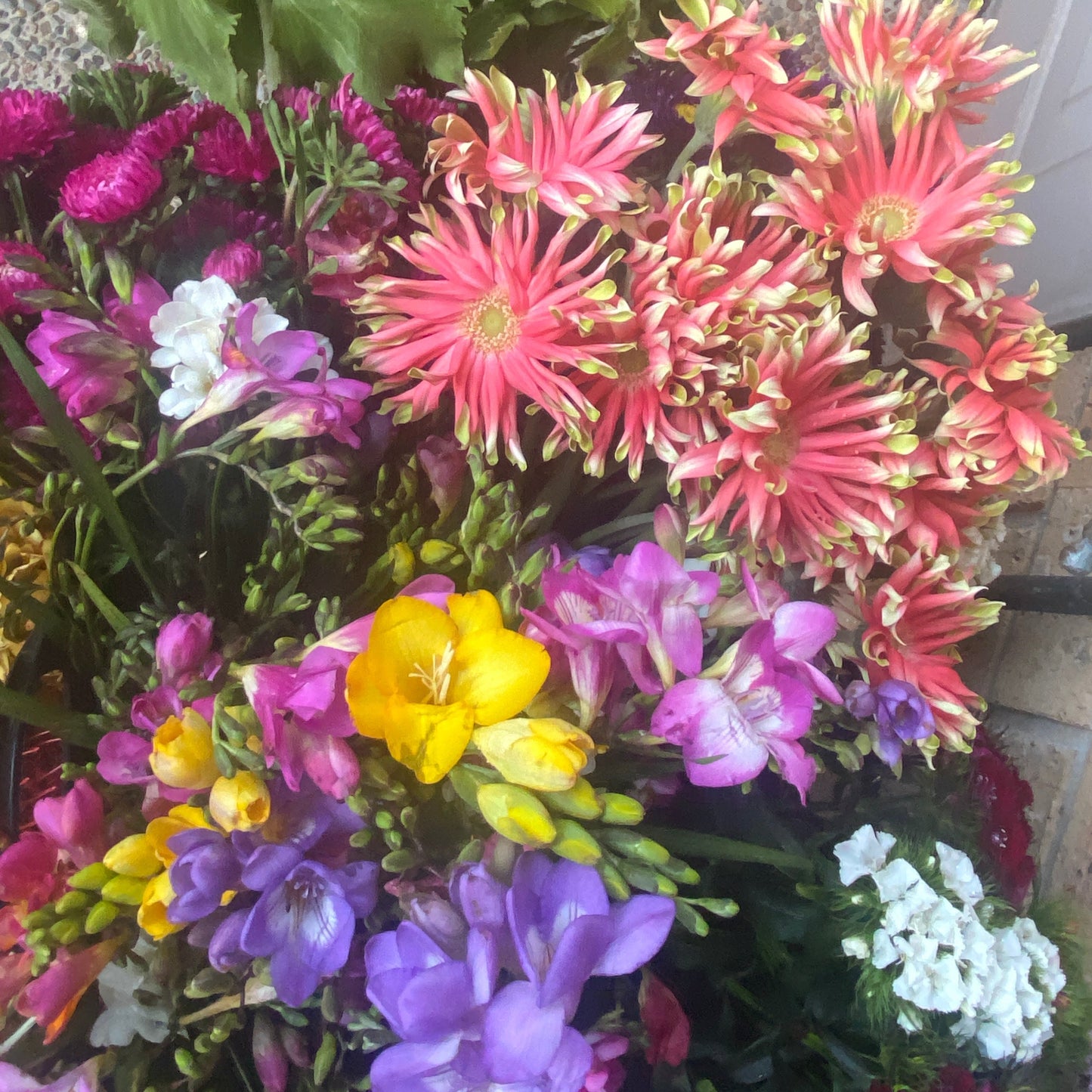 Bright seasonal flowers of yellow, purple, pink and white arranged by Bold Botanicals